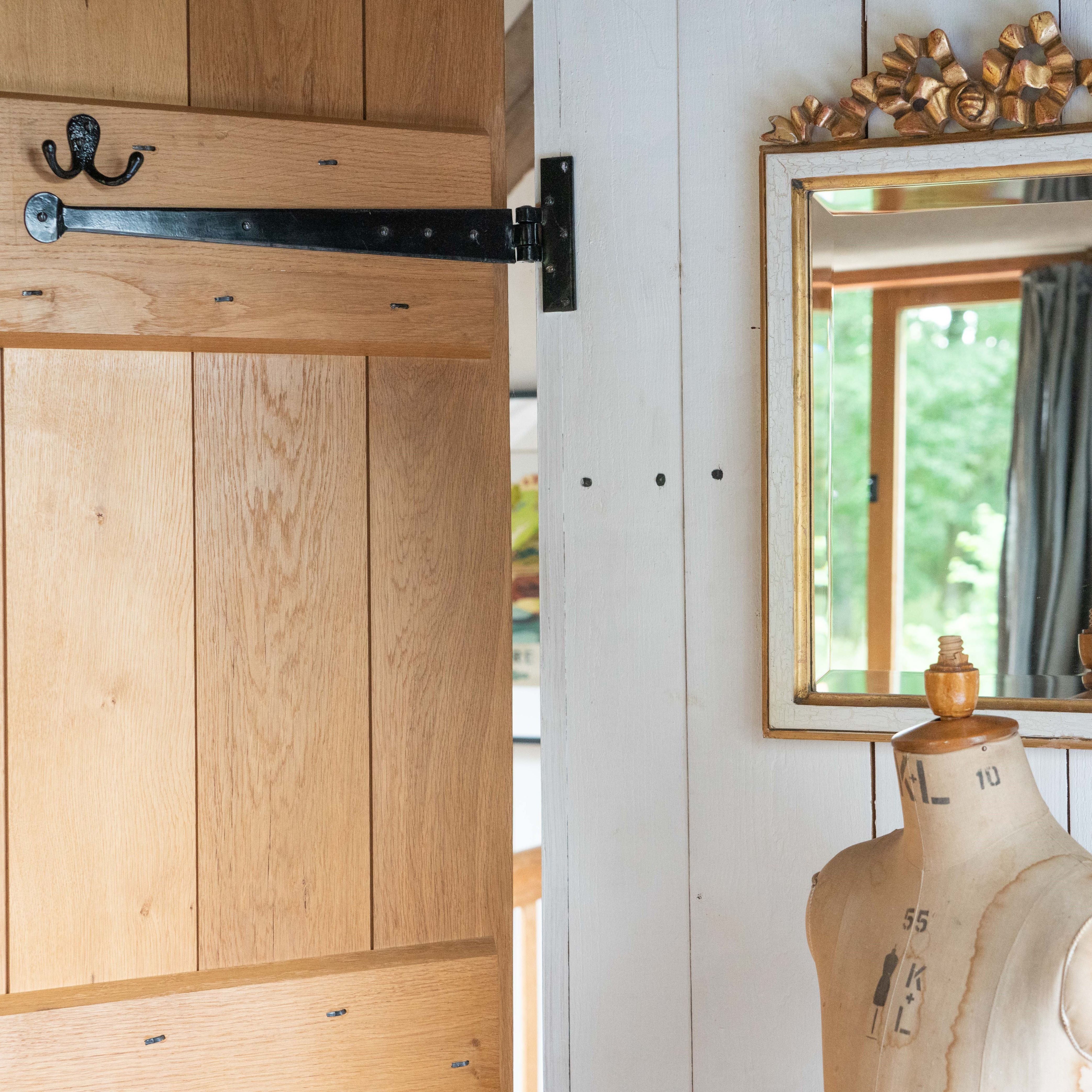 Studs fitted to a ledge & brace door with a Black T hinge & matching robe hook, next to a white panelled wall with a gold framed mirror and sewing dummy.