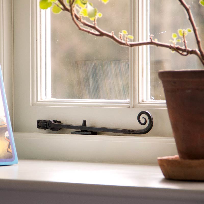 From The Anvil Beeswax Monkeytail window stay hardware on a white window frame