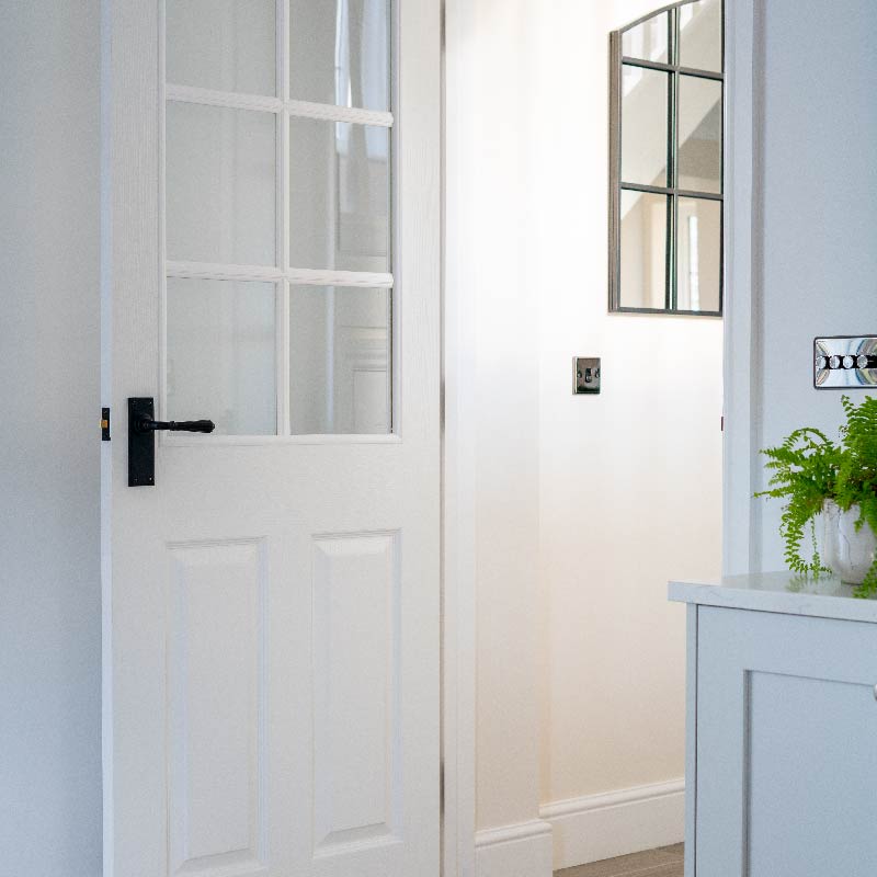 Black door handle on a white glazed and panel wooden door