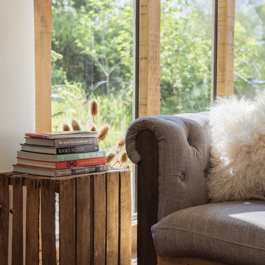 Rustic home interior with a crate side table, wooden beams, and a pile of books
