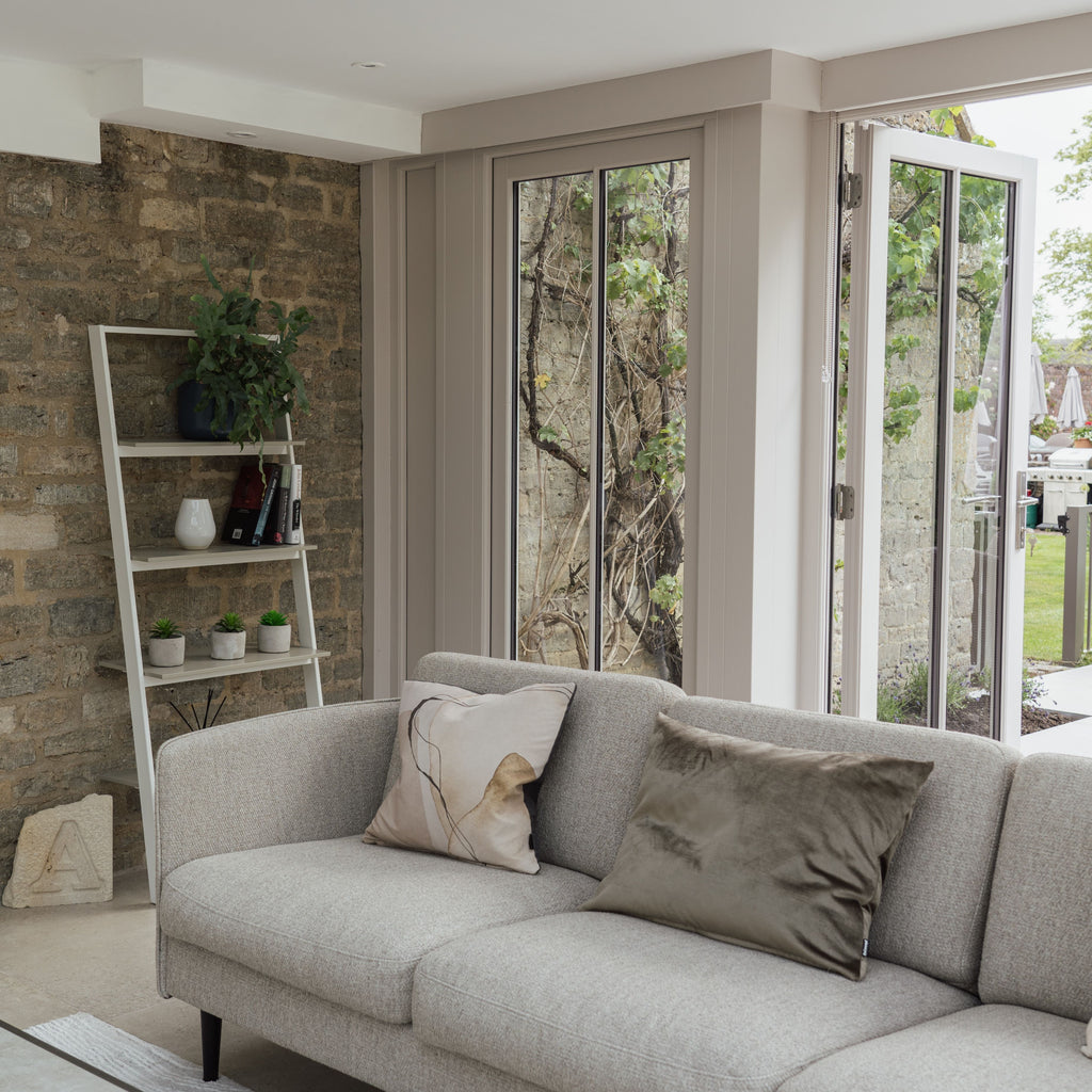 Modern conservatory with brick wall and neutral sofa and cushions.