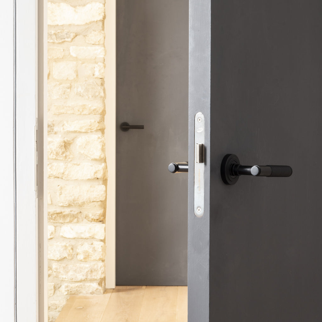 Grey open door with From The Anvil's Matt Black Brompton knurled door handle.
