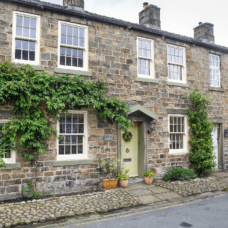 Stone cottage with a painted wood door with From The Anvil external door hardware
