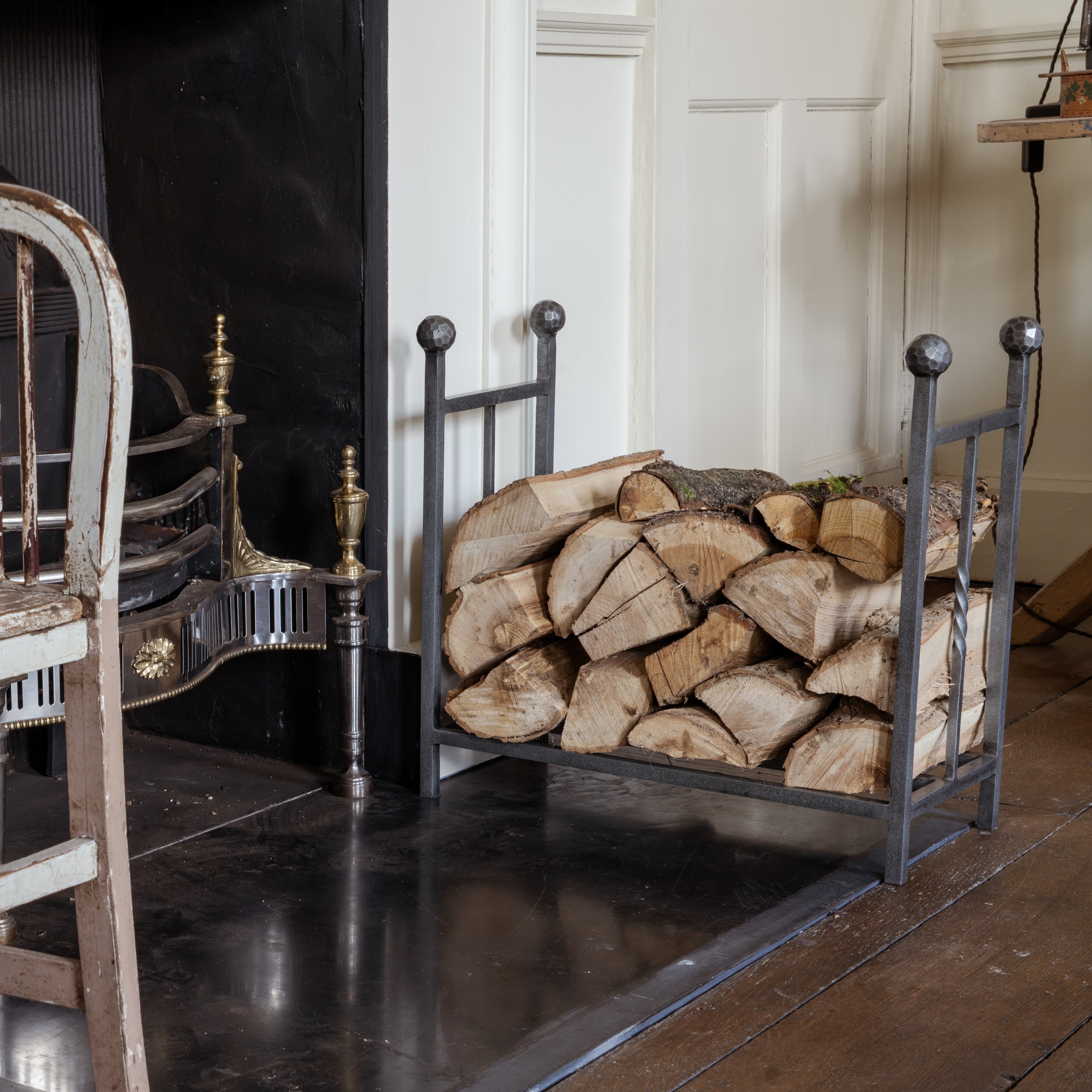From The Anvil Pewter fireside log holder by an antique fireplace