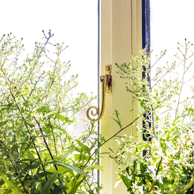From The Anvil's Polished Brass Monkeytail period window espagnolette on a white frame