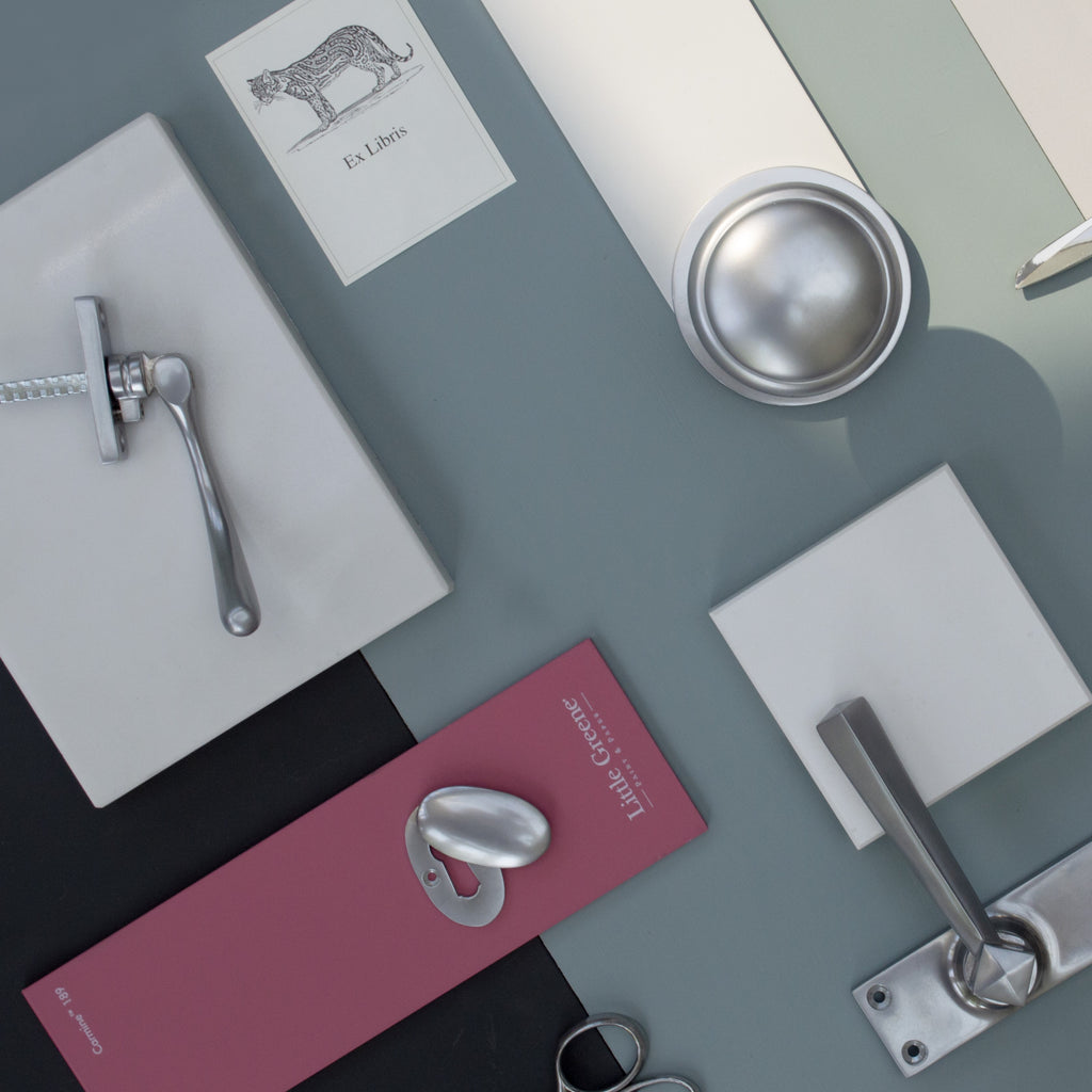 Satin Chrome mood board with pink, grey and blue backgrounds and Satin Chrome escutcheon, door handle, door knob, and hinge and pair of scissors.