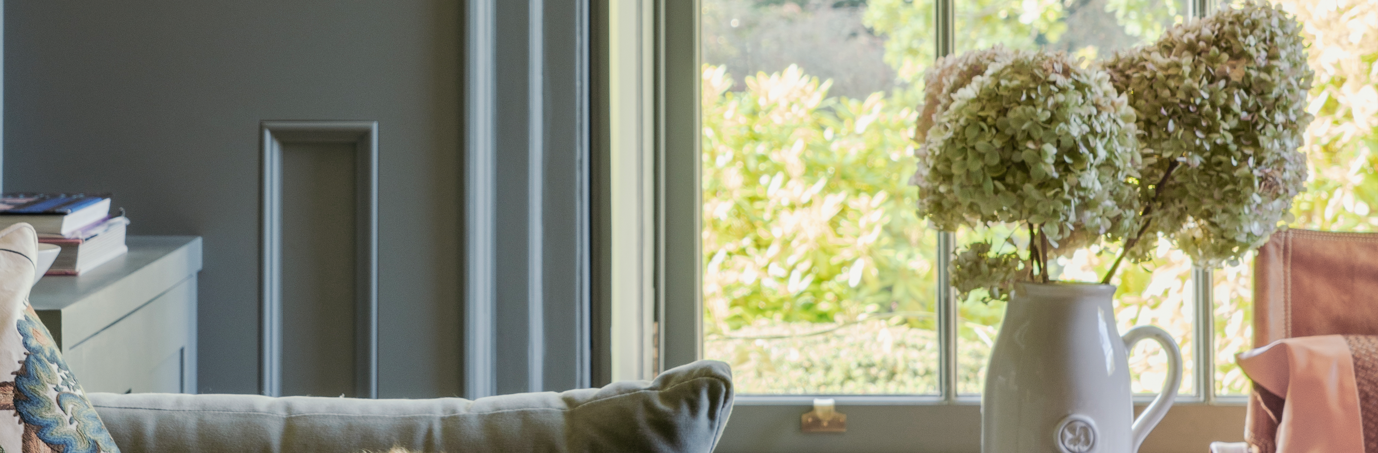 Blue panelled walls, sash window with Brass sash window hardware, and pink and blue soft furnishings.