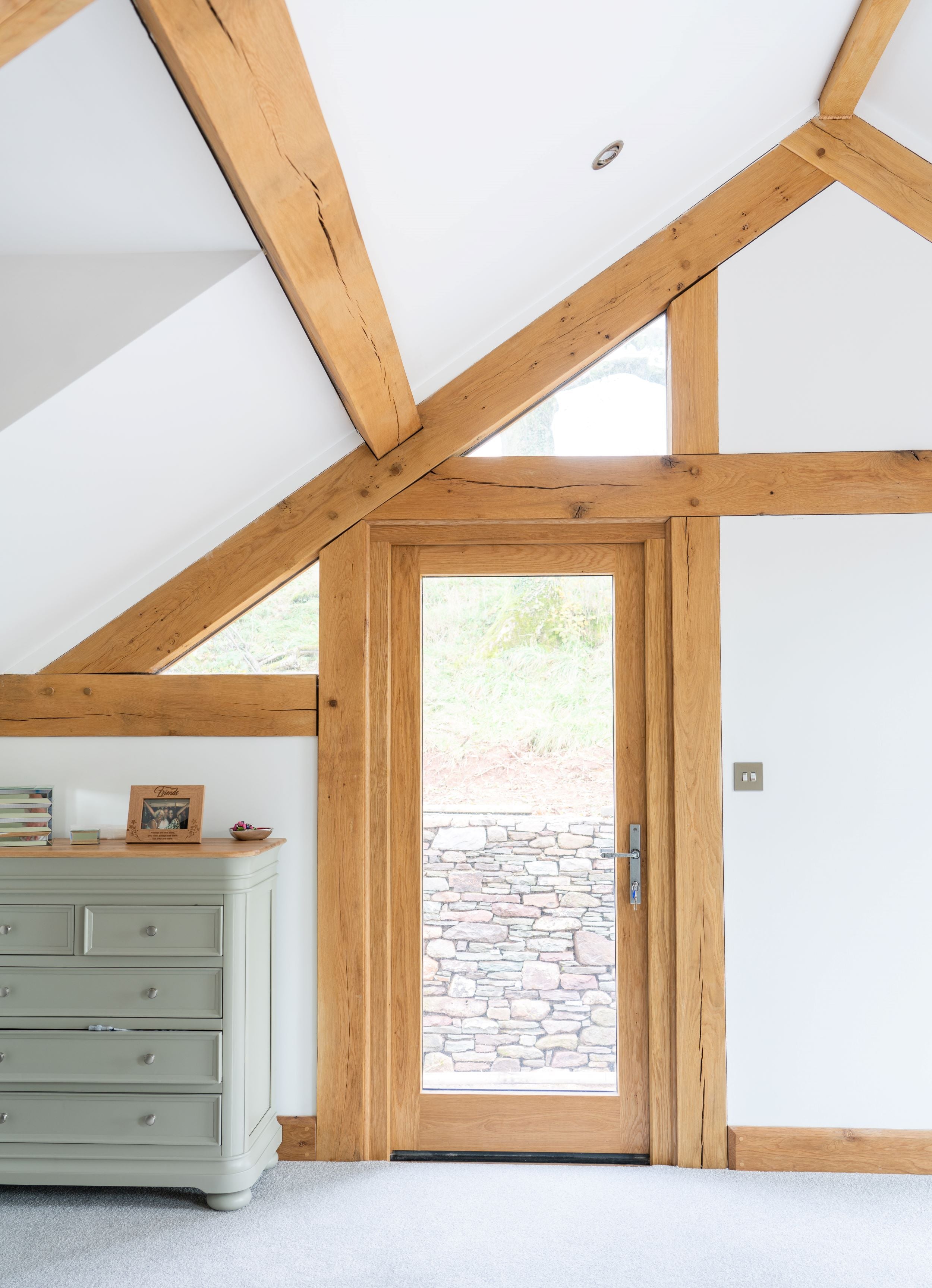 Contemporary bedroom with wooden beams and a glazed door fitted wtih From The Anvil Pewter door handle and butt hinges.