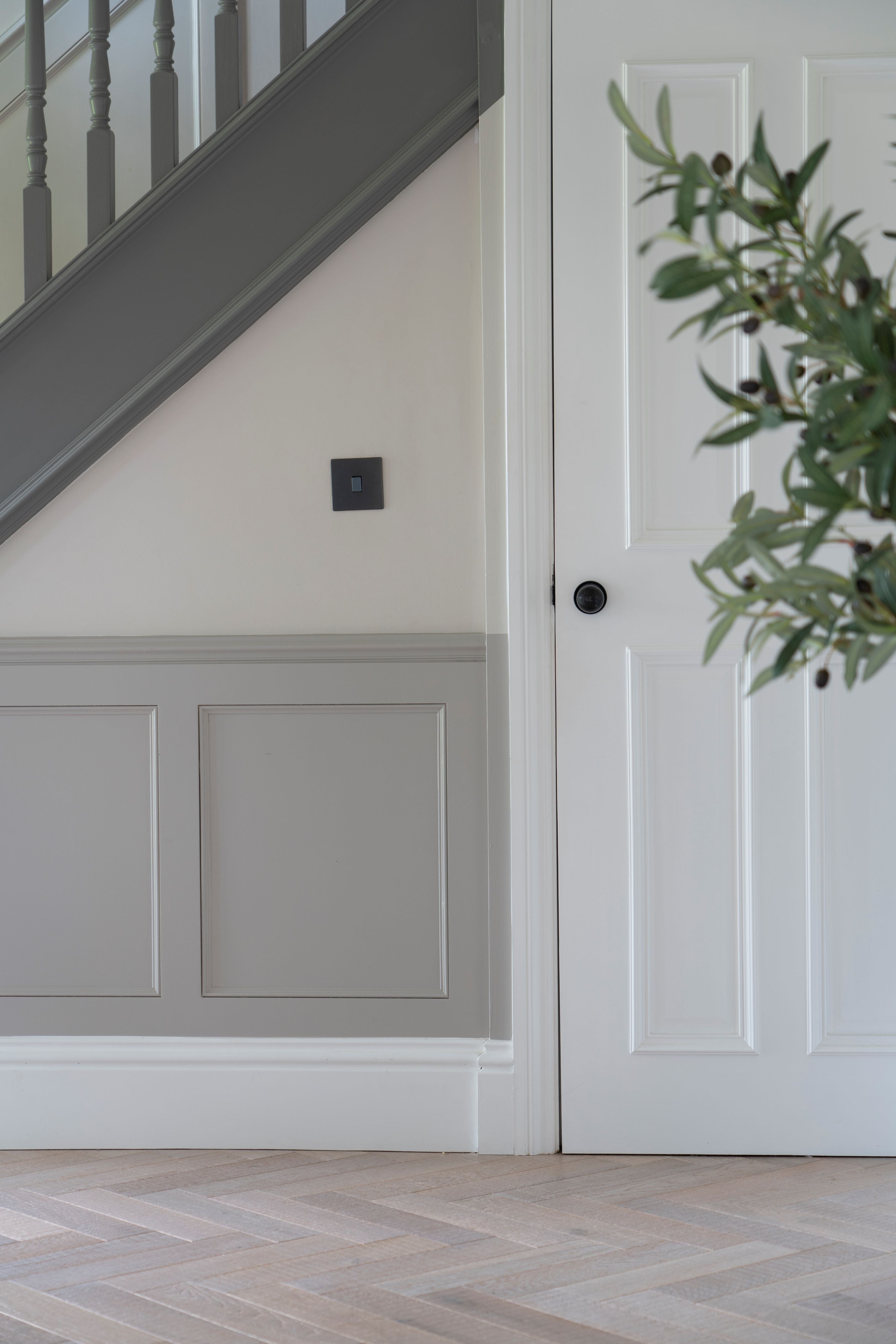White panelled door under grey painted staircase, with Aged Bronze Mushroom From The Anvil door knob handle