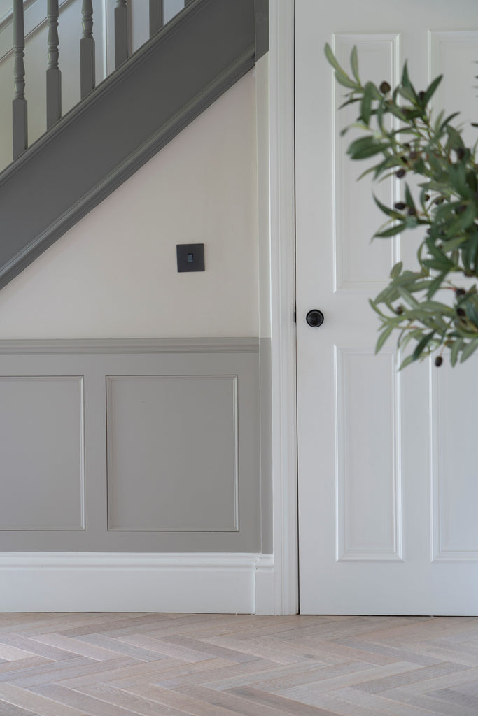 White panelled door under grey painted staircase, with Aged Bronze Mushroom From The Anvil door knob handle