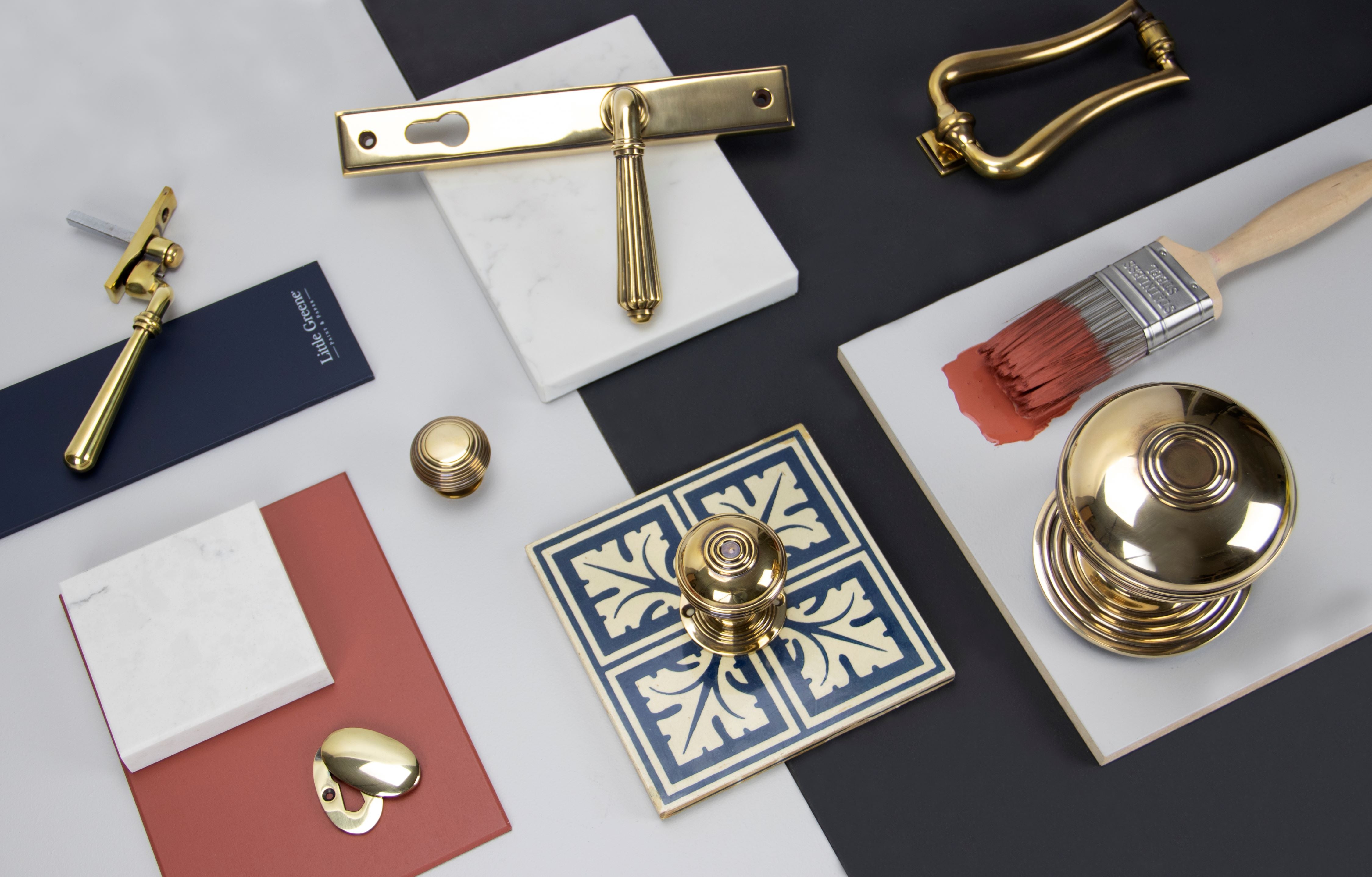 Ironmongery moodboard with Aged Brass cabinet knobs, escutcheon, door handle, door knocker, window hardware and ceramic and marble tiles with navy blue and red paint swatches.