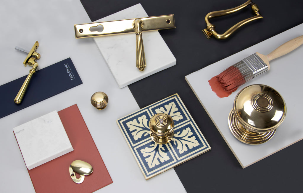 Ironmongery moodboard with Aged Brass cabinet knobs, escutcheon, door handle, door knocker, window hardware and ceramic and marble tiles with navy blue and red paint swatches.