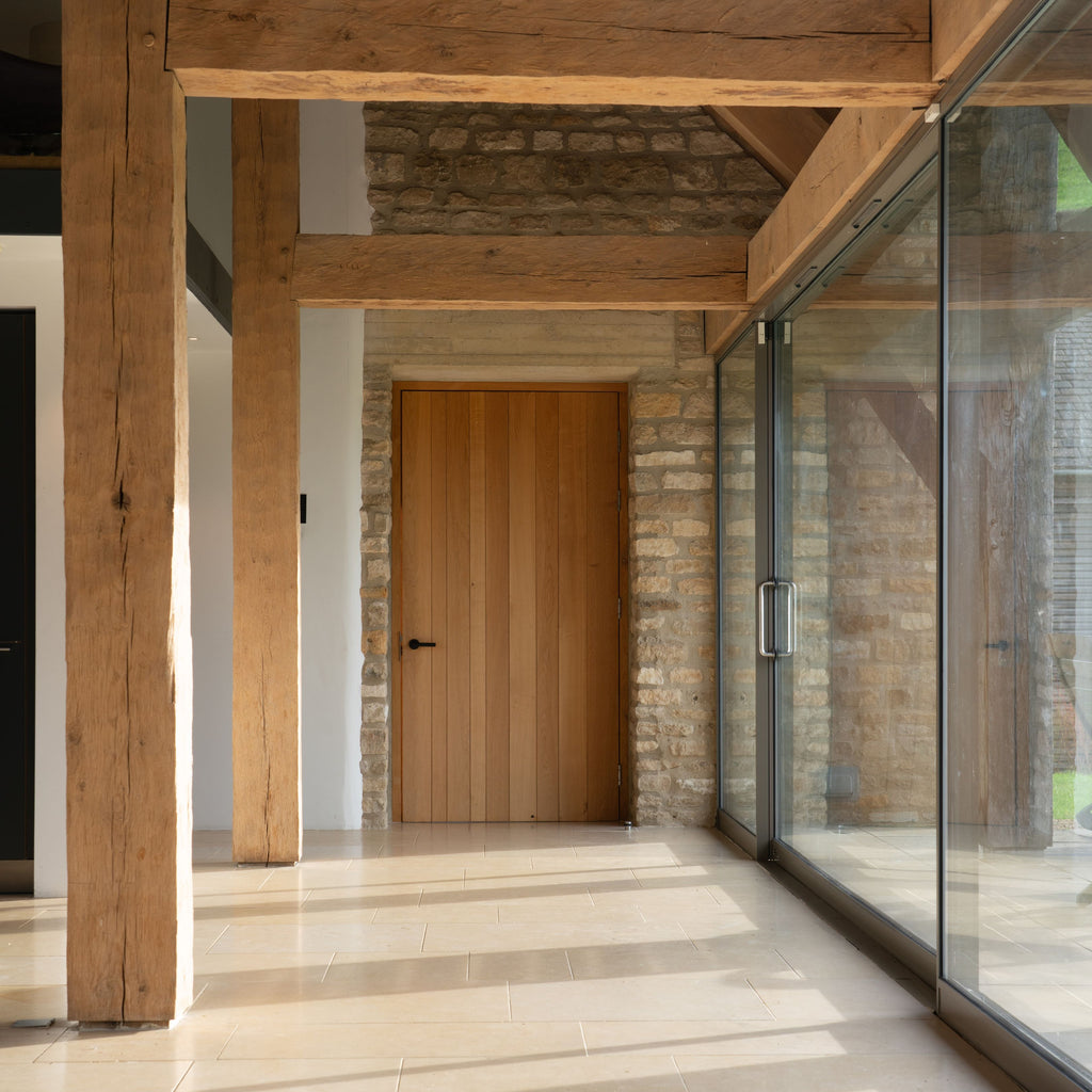 Contemporary hallway with big glass windows and wooden door with From The Anvil's Matt Black Brompton knurled door handle.