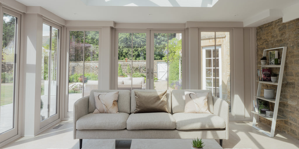Neutral sofa with cushions in a modern conservatory.