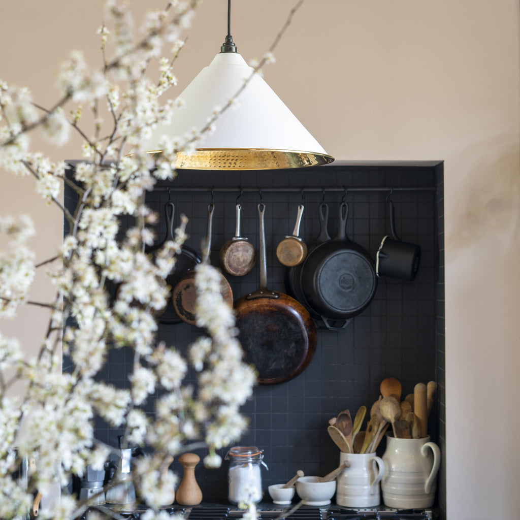 Hammered Brass Hockley ceiling pendant light in a neutral and black kitchen with hanging utensils.