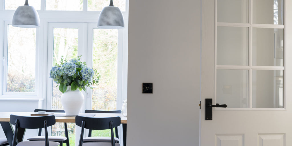 White panelled glazed interior door with a From The Anvil Black door handle, leading into a dining room.