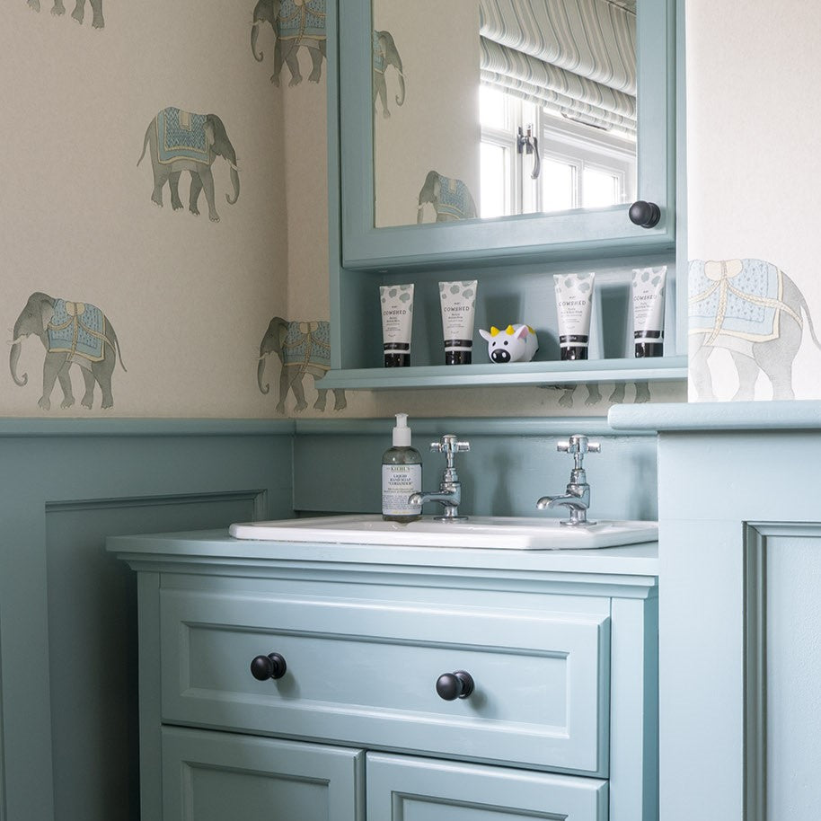 Pale blue panelled sink unit with Aged Bronze Mushroom cabinet knobs in a bathroom.