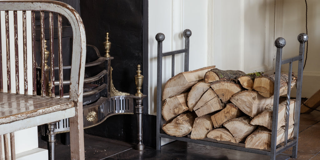 From The Anvil Pewter Rectangular log holder filled with logs by an ornate fireplace.