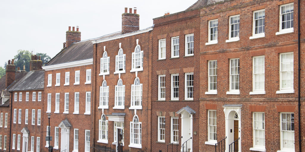 Row of red brick Period townhouses with white sash windows.