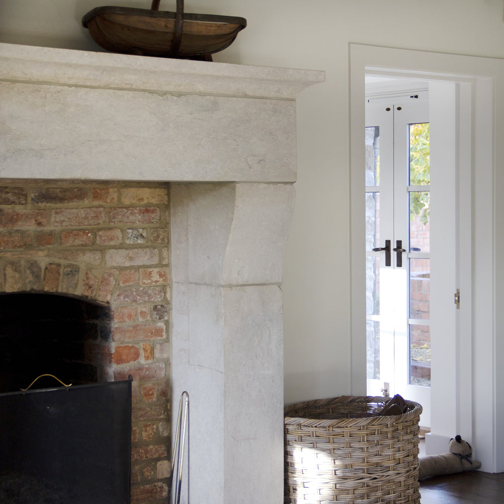 Stone fireplace next to wicker basket with white door in background with From The Anvil Black door handles.