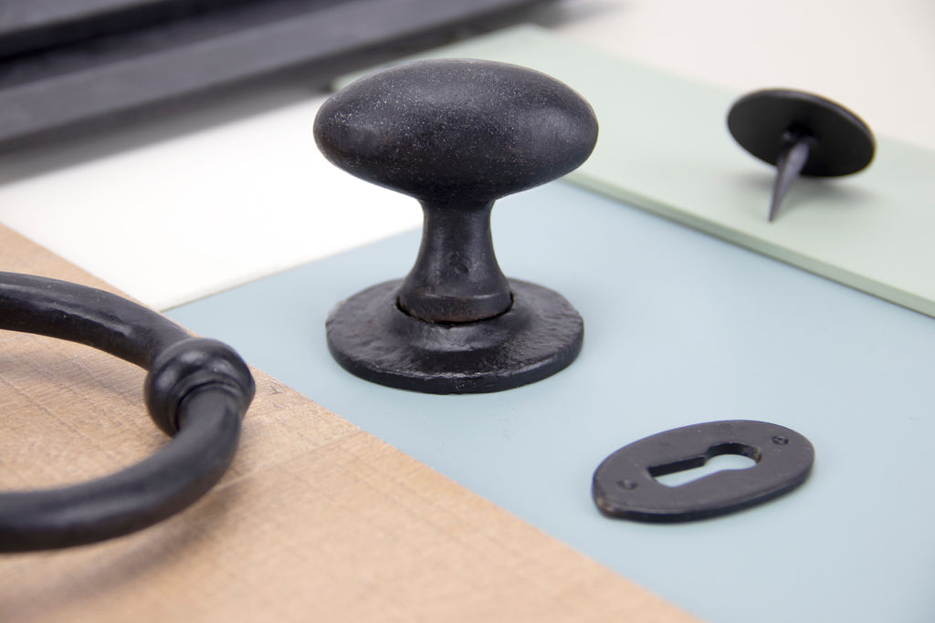 Ironmongery mood board with green, blue and wooden background, featuring our External Beeswax cabinet knob, escutcheon, pin & door knobs.