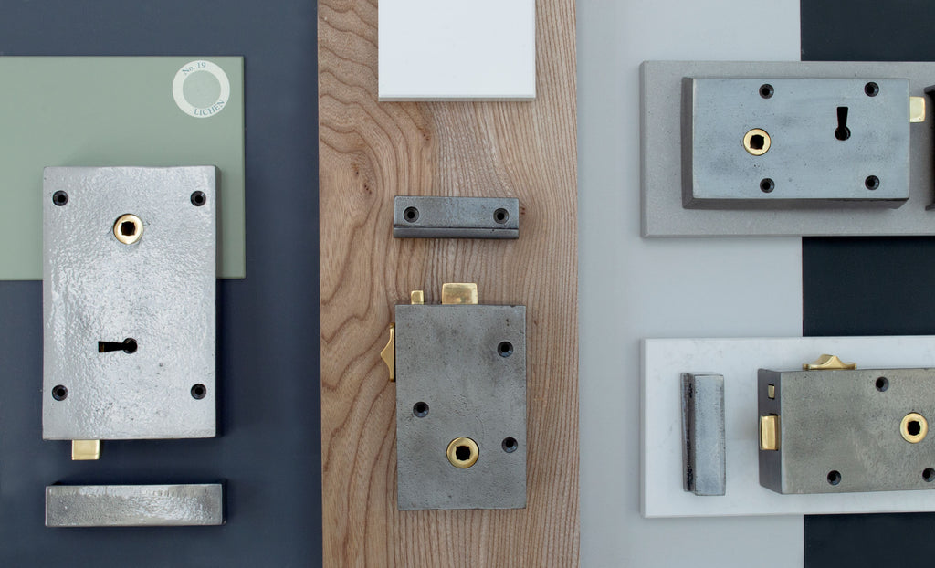 Ironmongery mood board with navy, green, white & black background, slab of wood, and four Iron locks.