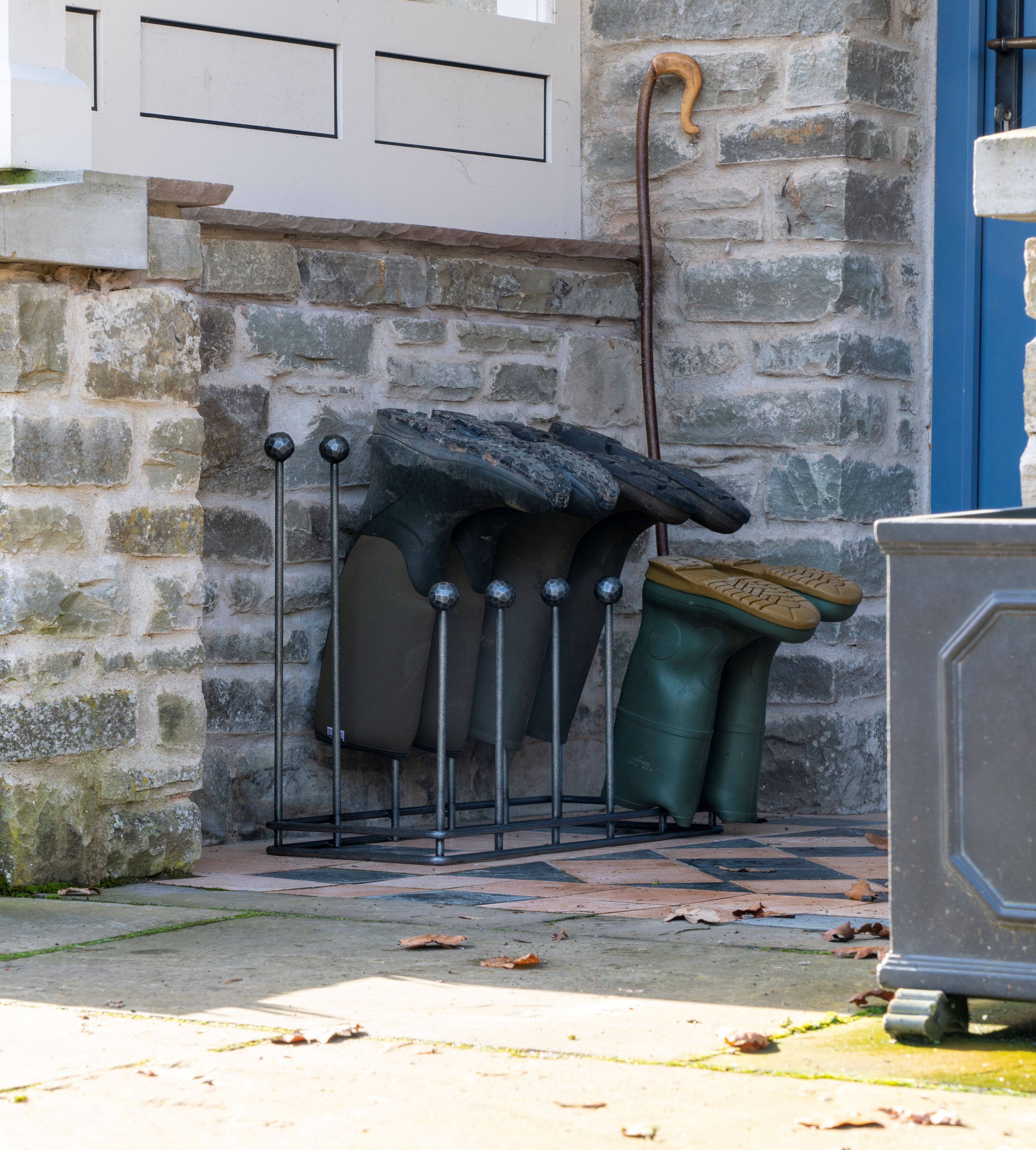 From The Anvil's Pewter welly boot rack outdoors by a brick wall