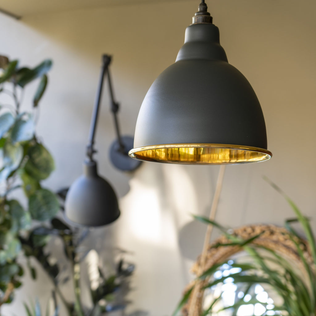 From The Anvil's Smooth Brass Brindley pendant painted in a slate grey colour, hung in a natural room.