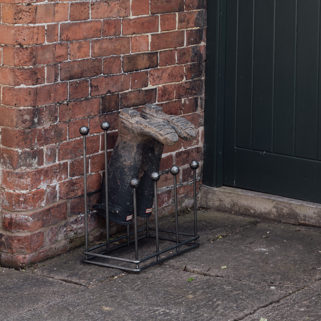 From The Anvil's Pewter welly boot rack outdoors by a brick wall