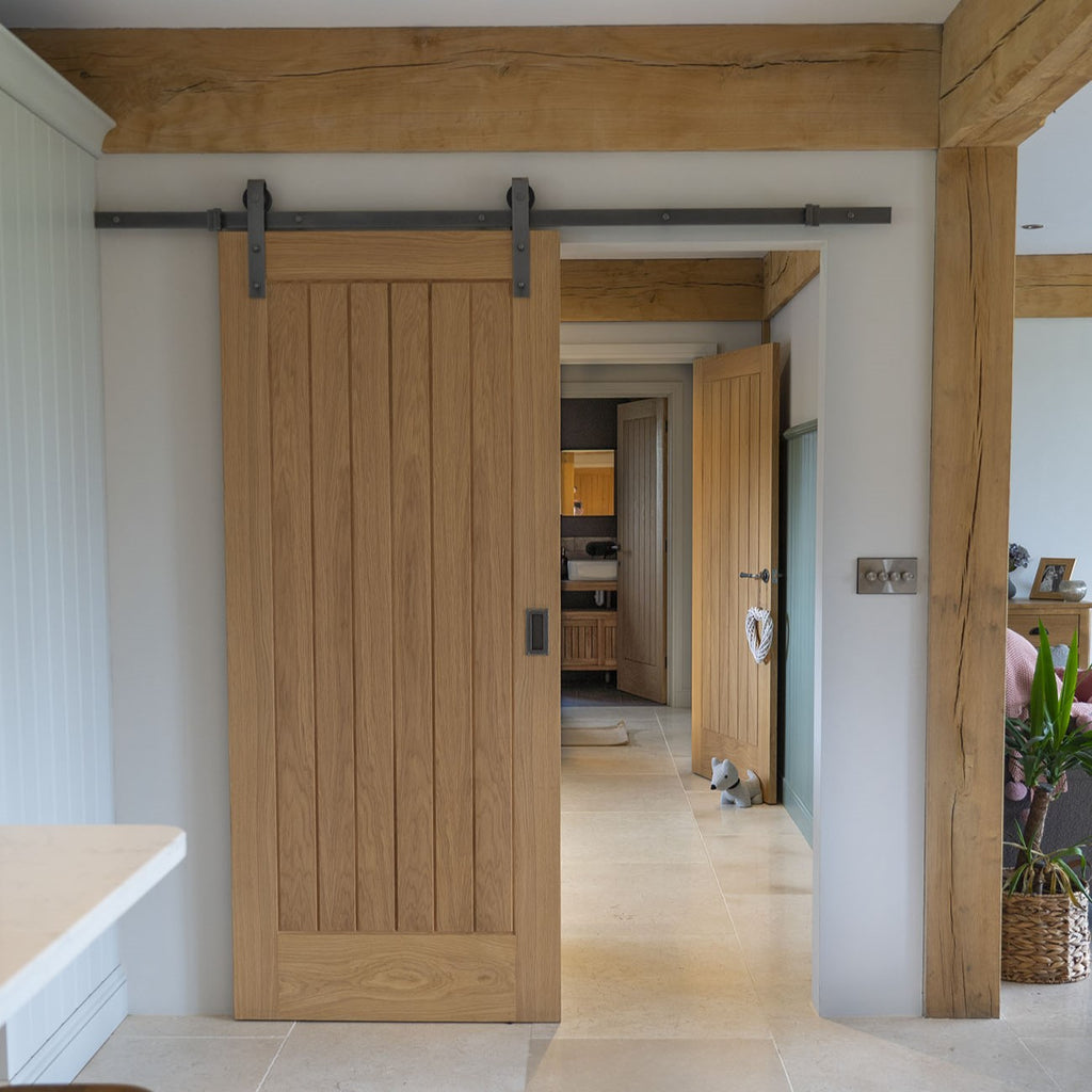 Oak panelled door fitted to a contemporary interior with a Pewter sliding door track and matching pull handle.